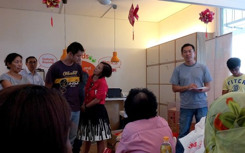 Outreach worker Erwin, in gray, briefs volunteers on a house visit activity.